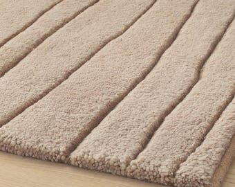 Alfombra de lana neozelandesa anudada a mano: diseño de agua que fluye en tonos beige y marrón.