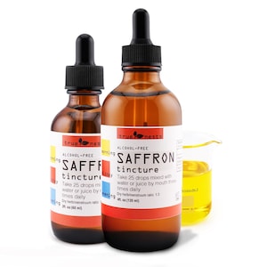 Puede incluir: Dos frascos de vidrio ámbar de tintura de azafrán con cuentagotas negros y etiquetas blancas. Las etiquetas dicen "ALCOHOL-FREE SAFFRON tincture". También hay un pequeño vaso de precipitados con líquido amarillo. Los frascos son de 60 ml y 120 ml.