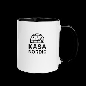 Può includere: Tazza in ceramica bianca con interno e manico neri. La tazza presenta un logo in bianco e nero con la scritta "KASA NORDIC" sotto un'illustrazione di un igloo. La tazza è su uno sfondo nero.
