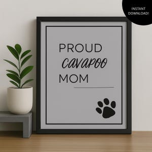 Könnte beinhalten: Gerahmter Druck mit den Worten "PROUD Cavapoo MOM" in schwarzer Schrift auf grauem Hintergrund. Ein schwarzer Pfotenabdruck befindet sich unten rechts. Der Rahmen ist schwarz.
