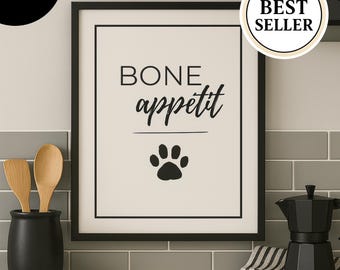 May include: A framed print with the words "BONE appetit" and a paw print in black. The print is in a black frame and is on a light beige background. A black coffee maker and a black utensil holder with wooden spoons are also visible.
