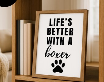 May include: A framed print with the text "LIFE'S BETTER WITH A boxer" in black, along with a paw print. The frame is a light brown color, and the print is displayed on a shelf with books.
