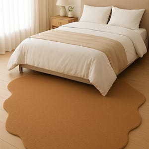 Puede incluir: Una escena de dormitorio con una cama con ropa de cama blanca y un camino de cama beige. Una alfombra beige de forma irregular se encuentra en el suelo de madera. También se ve una mesita de noche con una lámpara y decoración.