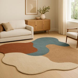 Puede incluir: Una alfombra abstracta con forma orgánica, en tonos óxido, azul y beige. Está ubicada en un salón con sofá y silla, creando un diseño moderno y artístico. Las dimensiones de la alfombra no son visibles.