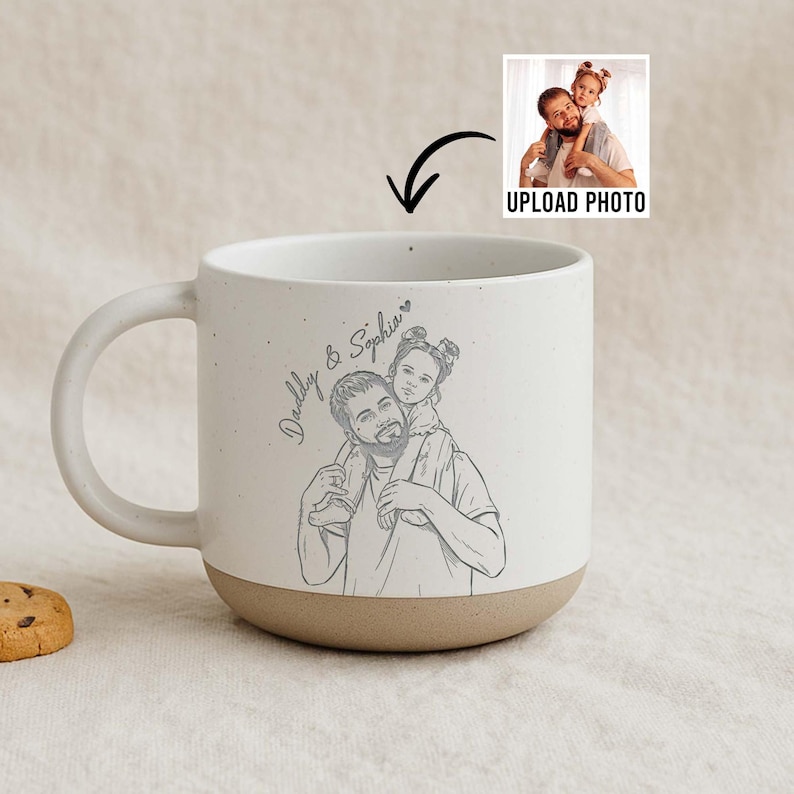 May include: A white ceramic mug with a tan base and handle. The mug features a sketch of a father carrying a child on his shoulders, with the text "Daddy & Sophia". An image of a father and child is shown with the text "UPLOAD PHOTO".
