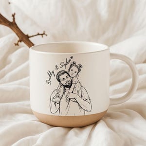 May include: Cream-colored ceramic mug with a tan base and a large handle. The mug features a black and white illustration of a father carrying a child on his shoulders, with the text "Daddy & Sophia".