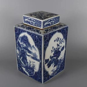 Op de afbeelding: Een vierkante, blauw-witte keramische pot met bijpassende deksel. De pot heeft landschaps- en bloemmotieven in een traditionele Aziatische stijl. De deksel en het lichaam zijn versierd met ingewikkelde patronen en scènes.