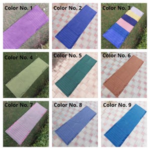 K&ouml;nnte beinhalten: Neun rechteckige Textilmatten in verschiedenen Farben werden gezeigt. Jede Matte ist mit einer Farbnummer versehen. Zu den Farben geh&ouml;ren Lila, Blau, Gr&uuml;n, Braun und Rosa. Die Matten haben ein gestreiftes Design und sind auf Gras oder einer gefliesten Oberfl&auml;che platziert.
