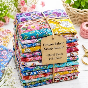 May include: A stack of folded cotton fabric squares featuring various floral block print patterns in vibrant colors including yellow, pink, blue, and purple. The bundle is tied with twine and includes a brown paper tag labeled Cotton Fabric Scrap Bundle -Floral Block Print Mix-.