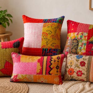 May include: A collection of five square and rectangular throw pillows featuring patchwork designs with intricate kantha stitching. The pillows display a vibrant mix of red, yellow, pink, and green fabrics with various floral and geometric patterns.