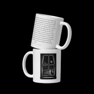 May include: Two white ceramic mugs stacked on top of each other. The top mug has text from a book printed on it. The bottom mug features a black and white illustration of a window with a street scene.
