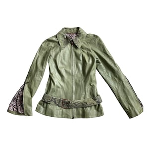 Może przedstawiać: Zielona skórzana kurtka z kołnierzem i paskiem ze skóry węża. Kurtka zapinana na zamek błyskawiczny i ma długie rękawy.