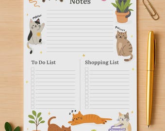 May include: A cat-themed notepad with sections for notes, a to-do list, and a shopping list. The notepad features cartoon illustrations of cats, yarn balls, and plants. A gold pen and paper clips are on the wooden surface.