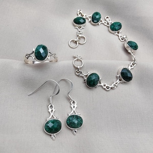 Peut inclure: Un ensemble de bijoux comprenant une bague, un bracelet et des boucles d'oreilles. Chaque pièce a un sertissage en métal argenté et est ornée de pierres précieuses ovales, facettées, vert foncé. Le bracelet a un fermoir à bascule.