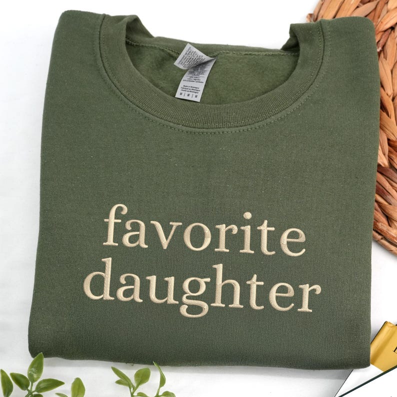 An military green sweatshirt embroidered with the phrase “favorite daughter” in a clean serif font.
The design is stitched in soft beige thread, creating a subtle and timeless contrast.
Minimal, cozy, and effortlessly stylish.