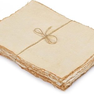 Op de afbeelding: Een stapel handgemaakt papier met gescheurde randen, vastgebonden met touw. Het papier heeft een warme, crèmekleur en een getextureerd oppervlak. Het touw is in een eenvoudige strik geknoopt. Het papier is geschikt voor schrijven of kunstprojecten.