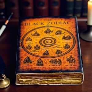 May include: An antique book, titled "The Black Zodiac", with an orange and black cover design. The cover displays zodiac symbols and the title. The book has gold-edged pages and is presented on a wooden surface, with other books in the background.