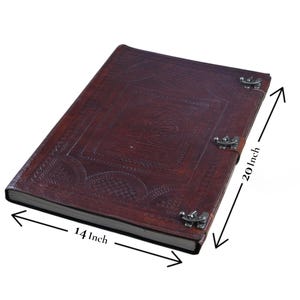 May include: A dark brown leather journal with embossed designs and metal clasps. The journal measures 14 inches wide and 20 inches long. The cover features a central embossed design and decorative patterns.
