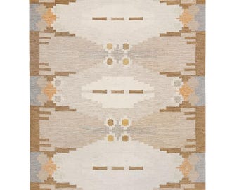 May include: A rectangular woven area rug featuring a repeating geometric pattern in shades of beige, cream, light gray, and muted gold. The design includes central diamond-like shapes with horizontal dashes and fringed edges on both ends.