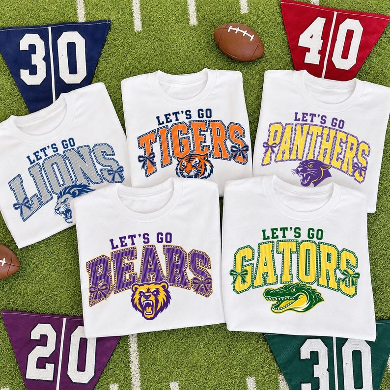 May include: Five white t-shirts featuring sports team graphics with the text Let's Go followed by team names Lions, Tigers, Panthers, Bears, and Gators. Each design includes a mascot illustration and decorative bows on the lettering.