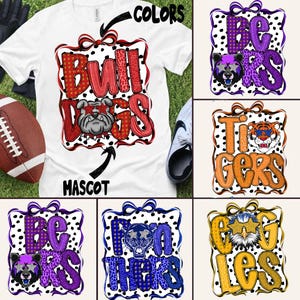以下が含まれることがあります： 赤と黒のブルドッグのデザインが施された白いTシャツ。デザインには、太字でテクスチャ加工されたフォントの「Bulldogs」という単語と、ブルドッグのマスコットが含まれています。シャツはフットボールとスニーカーと組み合わせています。