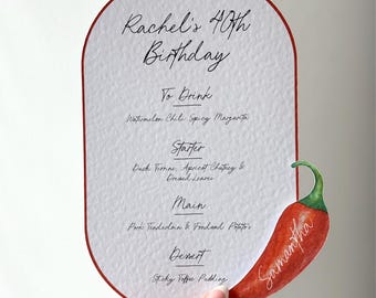 Puede incluir: Una tarjeta de menú blanca con borde rojo, con el texto "Rachel's 40th Birthday" y una lista de platos. Un pimiento rojo con el nombre "Samantha" está adjunto. El menú incluye "Watermelon Chili Spicy Margarita".