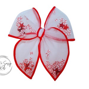 May include: A white mesh bow with red trim and red glitter stars. The bow is tied in a loop and has a center knot.