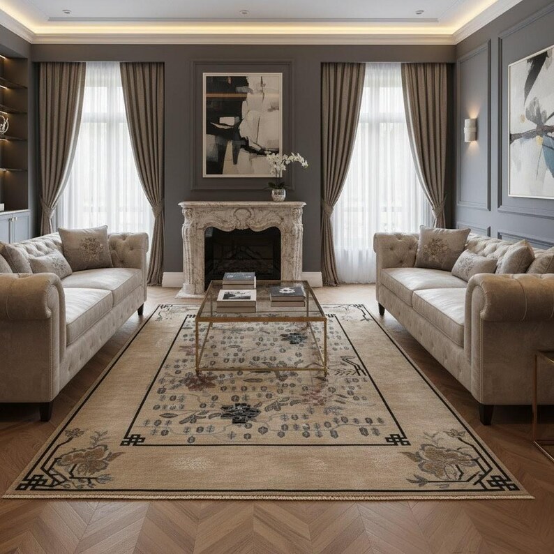 May include: A luxurious living room featuring two beige tufted sofas facing each other, a patterned rug, and a glass coffee table. The room has a fireplace, artwork, and large windows with beige curtains. The walls are painted a dark gray.