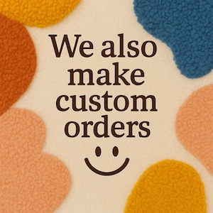 May include: A cream-colored textured fabric background featuring irregular, fuzzy, sherpa-like patches in mustard yellow, burnt orange, blue, and peach. Centered dark brown text reads "We also make custom orders" above a simple smiling face icon.