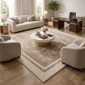 May include: A living room set featuring a cream-colored sofa and two matching armchairs arranged around a round white marble coffee table with a gold base. A dark wood executive desk with a black chair and a large area rug complete the space.