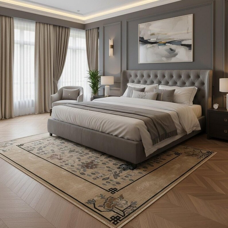 May include: A luxurious bedroom featuring a large bed with a tufted headboard, layered bedding, and decorative pillows. The room has gray walls, a patterned rug, and neutral-toned curtains. A painting hangs above the bed, and a small chair sits near the window.