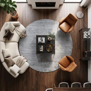 May include: An overhead view of a modern living room with a curved beige sofa, two brown leather armchairs, and a black marble coffee table. A gray circular rug sits in the center of the room on a hardwood floor.