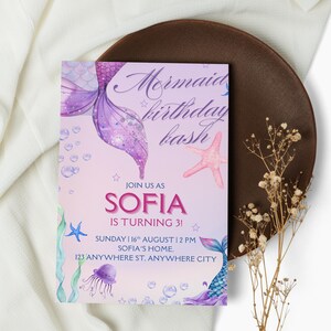 Può includere: Un invito di compleanno a tema sirena con il testo "Mermaid birthday bash". L'invito presenta uno schema di colori viola e rosa con illustrazioni di una coda di sirena, stelle marine e bolle. L'invito è per il 3° compleanno di Sofia.