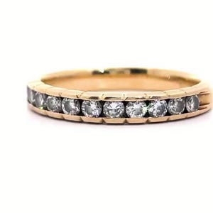 May include: A gold band ring with a row of clear gemstones. The ring has a classic design with a polished finish. The ring is set against a white background. The brand name "VEVA JEWEL" is at the bottom.