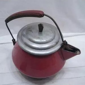May include: A red enamel kettle with a silver lid and a black handle. The handle has a red grip. The kettle has a spout and a black handle. The kettle is likely used for boiling water.
