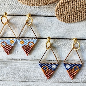 May include: Geometric beaded earrings with gold-tone metal frames. The earrings have a triangle shape with a beaded design in shades of brown, orange, blue, and white. The earrings have a post-back closure.