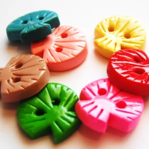 May include: Assortment of colorful plastic buttons shaped like leaves. The buttons are in shades of green, pink, red, brown, yellow, and blue.