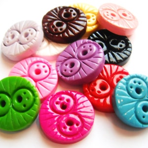May include: Assortment of colorful plastic buttons with a two-eye design. The buttons are in various colors, including pink, purple, green, blue, red, and brown.