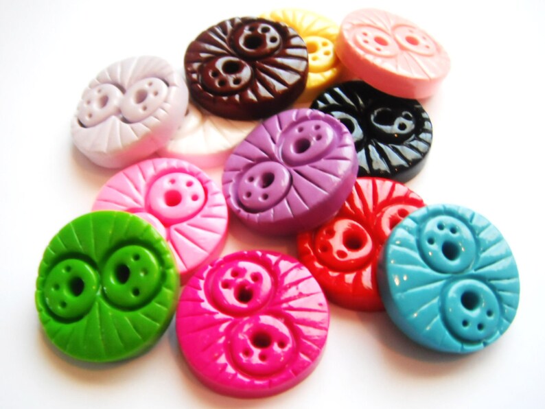 May include: Assortment of colorful plastic buttons with a two-eye design. The buttons are in various colors, including pink, purple, green, blue, red, and brown.