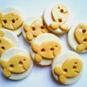 May include: A set of ten yellow and white buttons with a fish design. The buttons are about 1 inch in diameter.