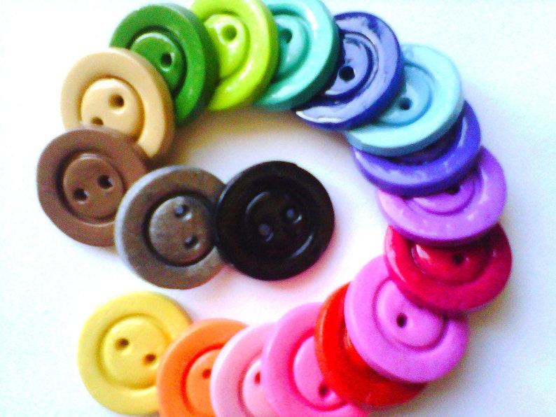 May include: A collection of colorful wooden buttons arranged in a spiral pattern. The buttons are all round and have two holes. The colors include green, yellow, blue, purple, pink, red, orange, brown, and black.