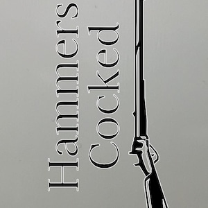 May include: A black and white illustration of a rifle with the words "Hammers Cocked" in a vertical layout. The rifle is depicted in a detailed, stylized manner, with a focus on its form and design.