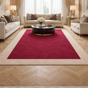 May include: A luxurious living room featuring a large, rectangular rug with a deep red center and a cream-colored border. The room includes cream-colored sofas, a round coffee table, and a crystal chandelier, creating an elegant atmosphere.