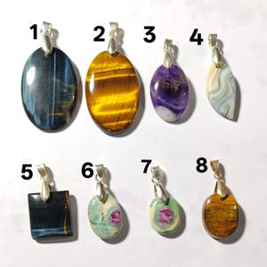 May include: Eight assorted gemstone pendants with silver-toned bails, numbered one through eight. The collection includes oval, square, and teardrop-shaped stones in various colours including blue, gold, purple, white, black, green, and pink.