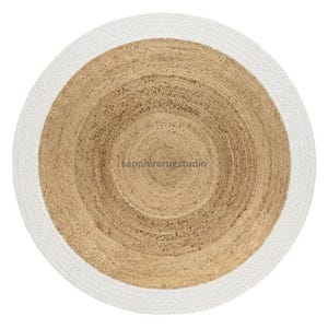 May include: A round jute rug with a white border. The center of the rug is a natural tan color, with concentric circles creating a textured pattern. The white border provides a clean contrast to the natural tones.