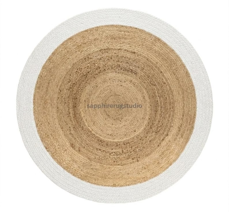 May include: A round jute rug with a white border. The center of the rug is a natural tan color, with concentric circles creating a textured pattern. The white border provides a clean contrast to the natural tones.