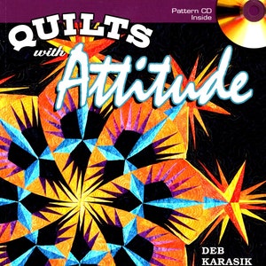 May include: A book cover with the title "Quilts with Attitude" in a bold, colorful font. The cover features a colorful quilt design with a starburst pattern in shades of orange, yellow, blue, and purple against a black background. The author's name, "Deb Karasik Quilt Maven", is printed in white at the bottom right corner. The text "Pattern CD Inside" is printed in white at the top right corner.