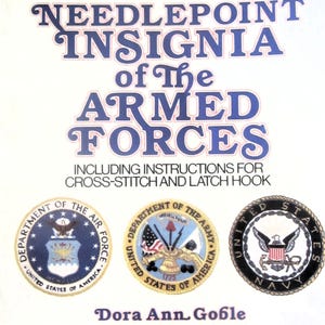 May include: A book cover titled "Needlepoint Insignia of The Armed Forces" with instructions for cross-stitch and latch hook. The cover features the logos of the Air Force, Army, and Navy. The author's name, Dora Ann Goble, is also displayed.