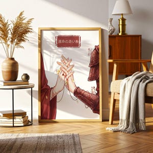 Könnte beinhalten: Ein gerahmter Kunstdruck mit einer Illustration von zwei Händen, die sich berühren, in einem rot-goldenen Farbschema. Das Kunstwerk enthält japanischen Text und ist in einem Raum mit neutraler Farbgebung ausgestellt.