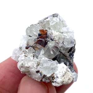 Puede incluir: Un grupo de cristales en bruto, con formaciones minerales transparentes, verde claro y marrón. Los cristales tienen un aspecto rugoso y texturizado, con una mezcla de bordes afilados y redondeados. La paleta de colores es una mezcla de blanco, transparente y tonos tierra.